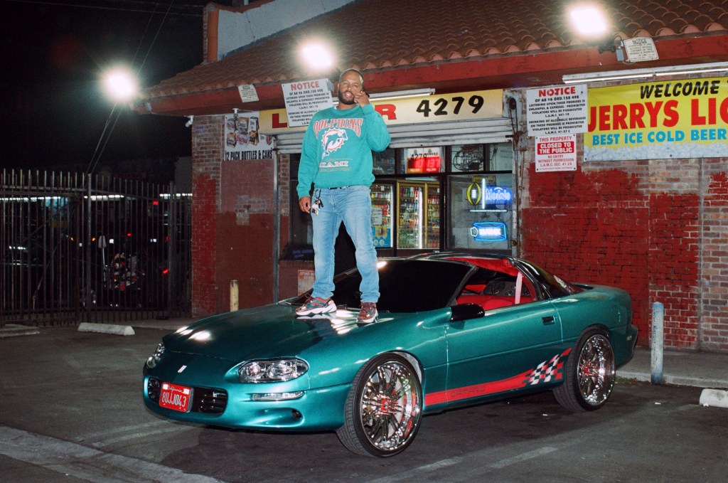 A man stands on his car bonnet