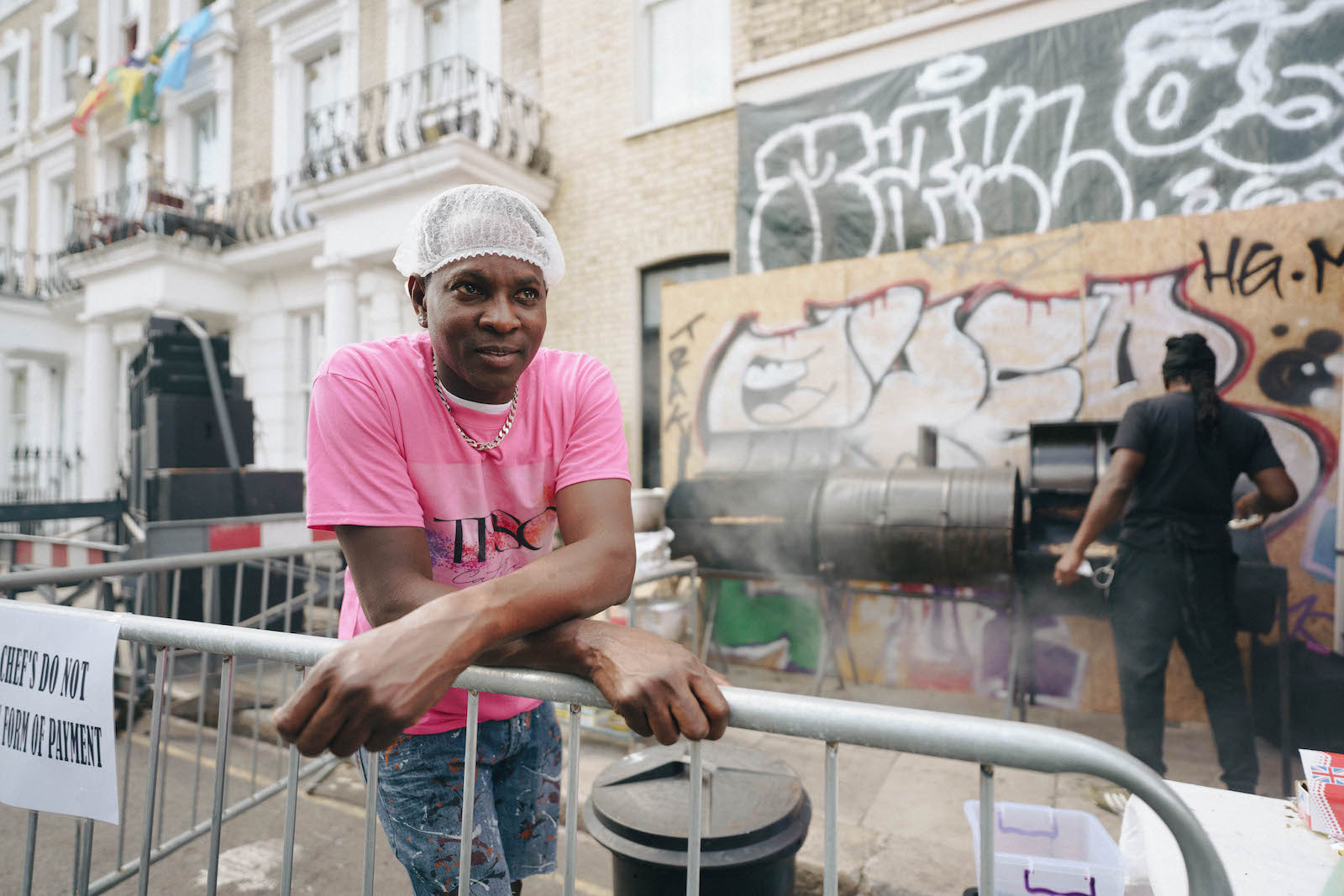 A man in a pink t shirt making food at Notting Hill Carnival 2022