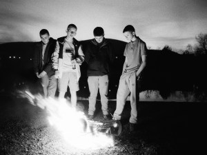 Four kids stand next to a fire